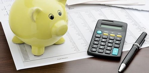 A piggy bank, calculator, pen and financial statement
